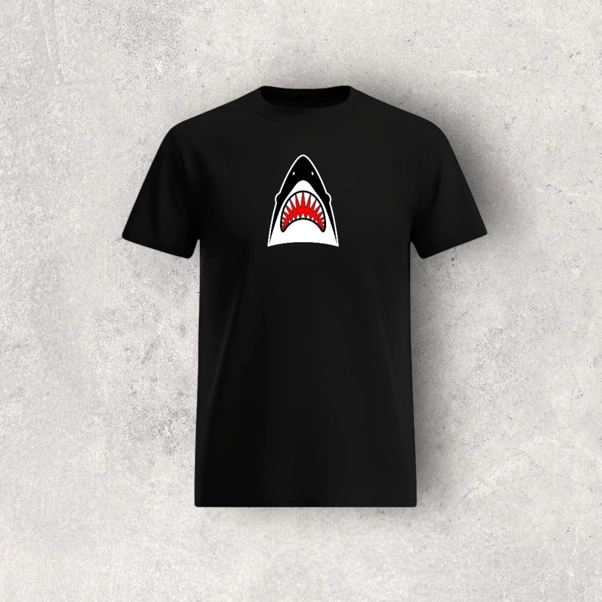 Black t-shirt with a shark graphic on a textured gray background