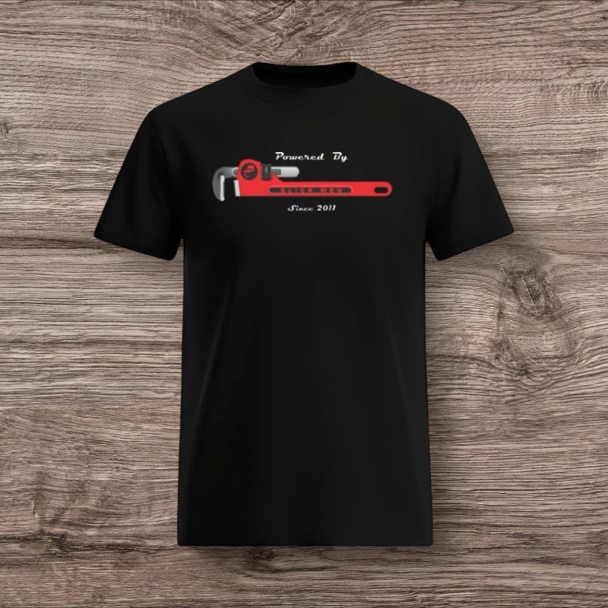 Black t-shirt with a plumber wrench design on a wooden surface