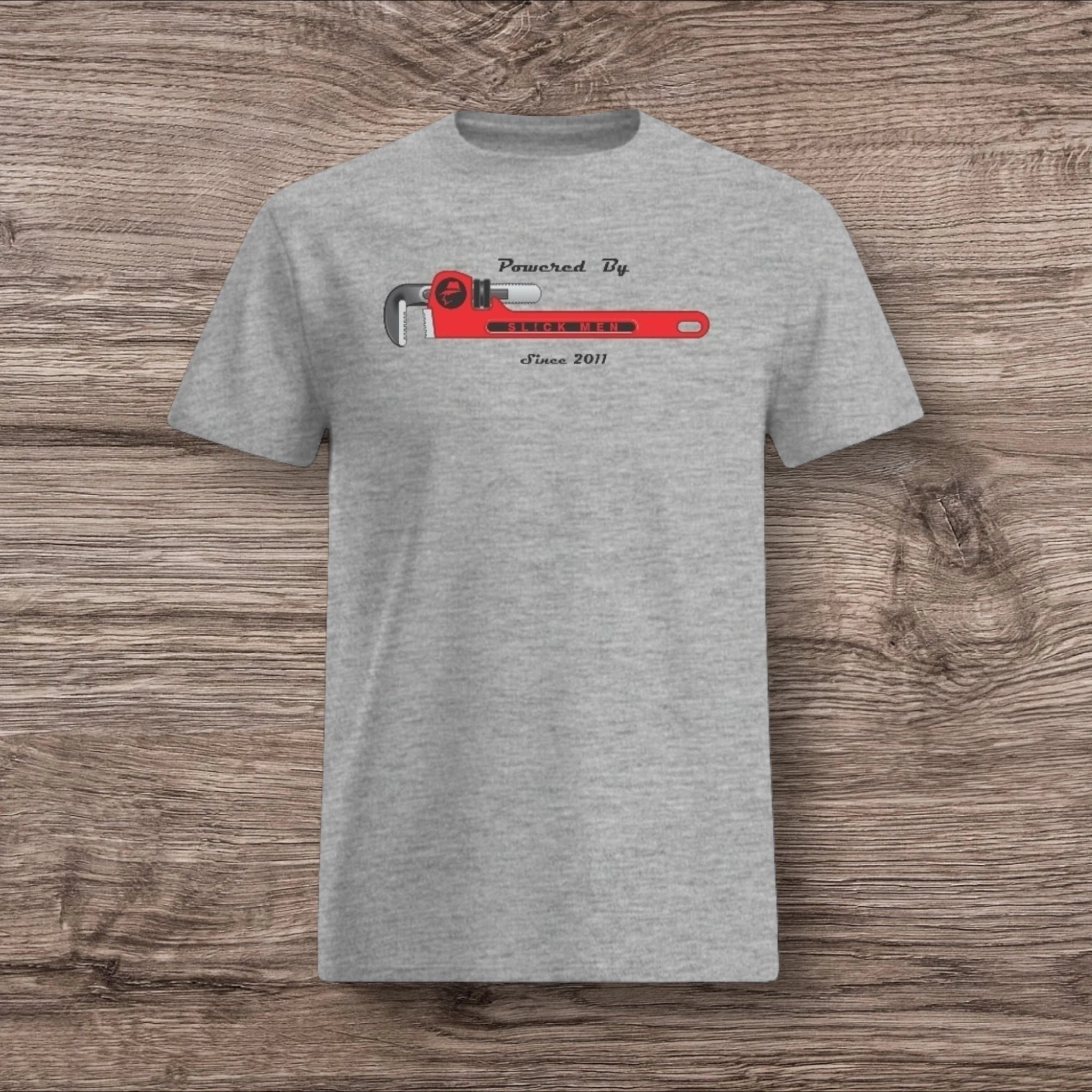 Sport gray t-shirt with a plumber wrench design on a wooden surface