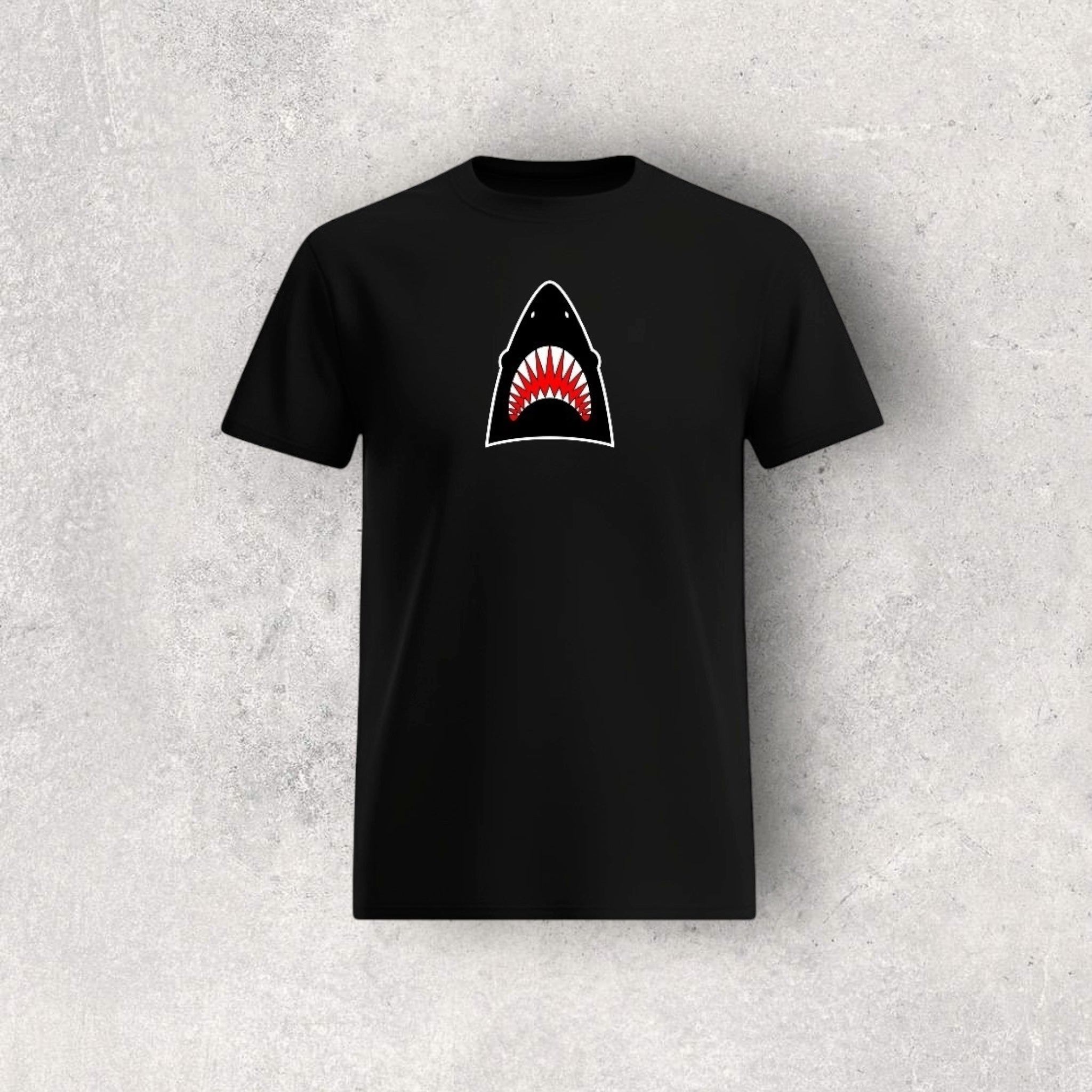 Black t-shirt with a shark graphic on a textured gray background