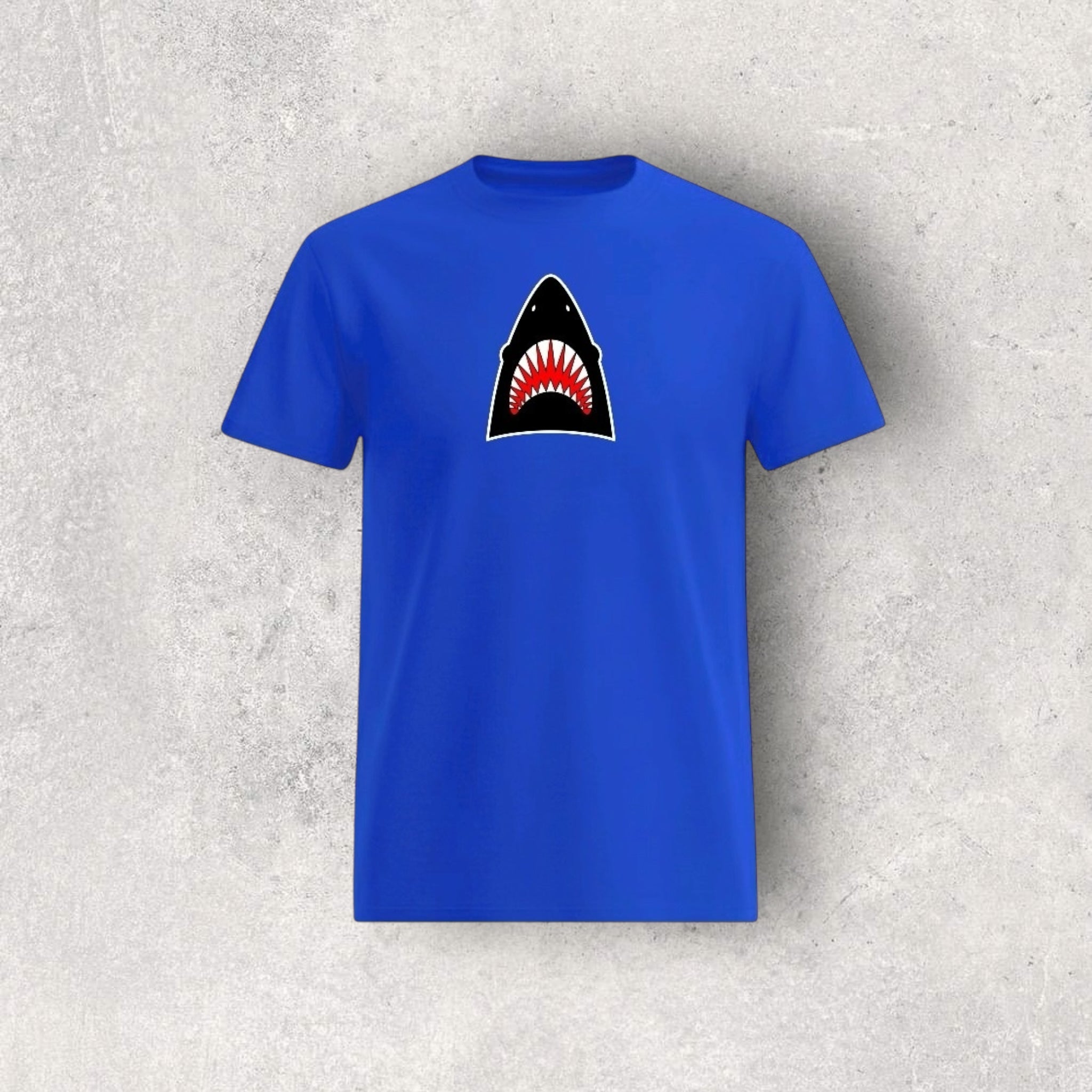 Blue t-shirt with a shark graphic on a textured gray background